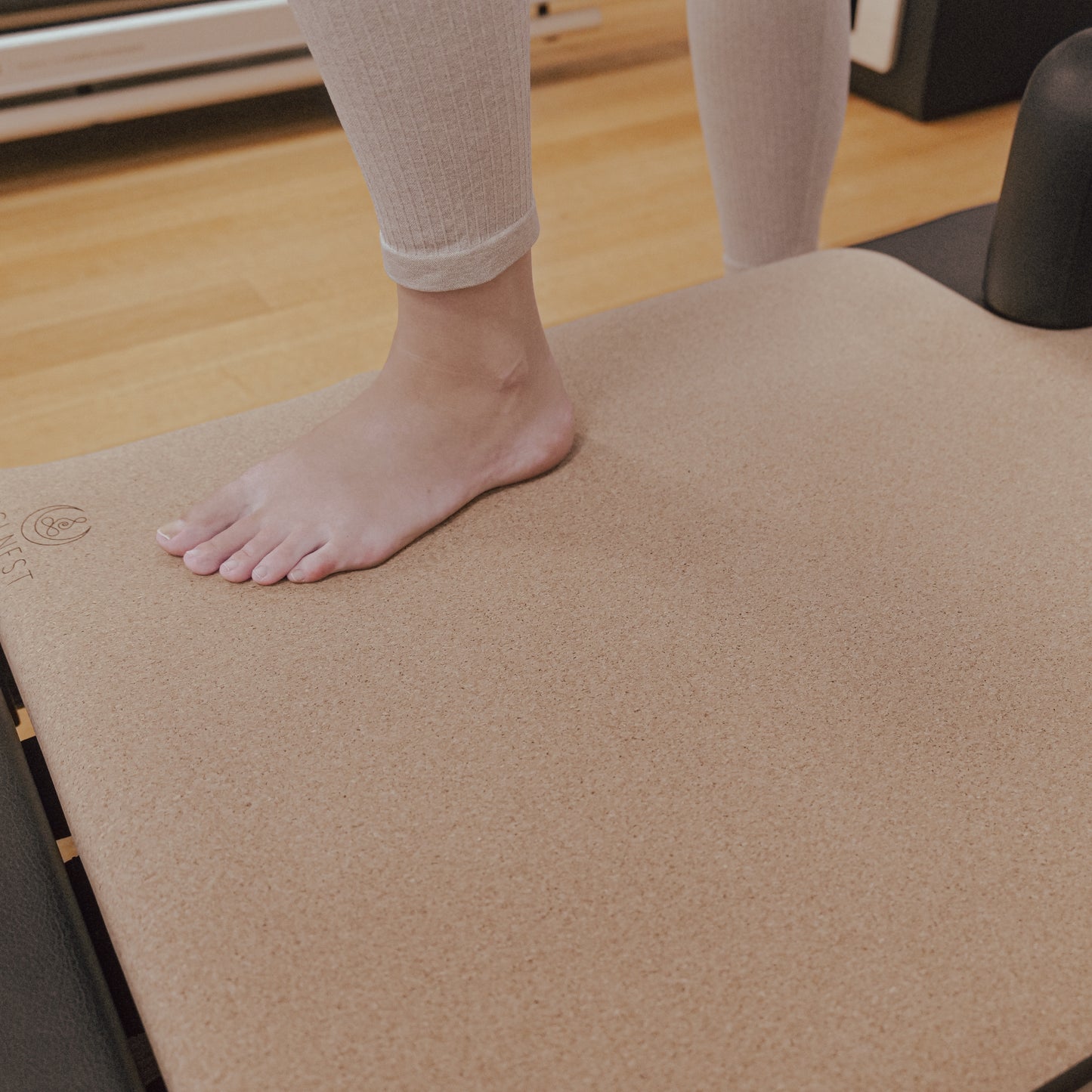 Woman standing on original cork and natural rubber Pilates reformer mat.