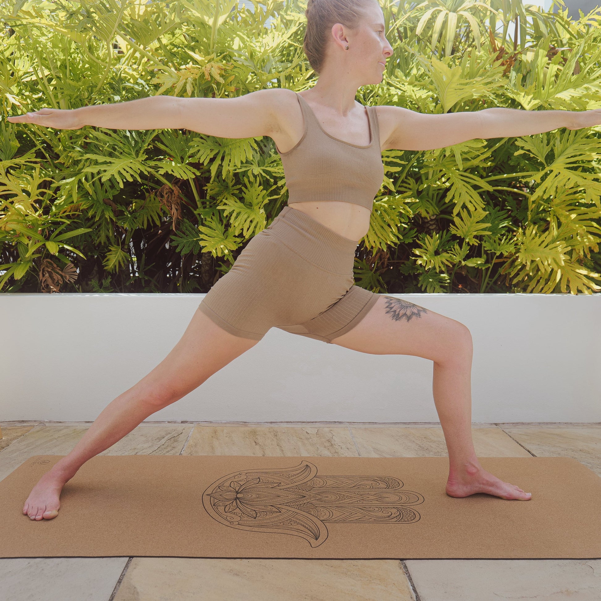 Woman performing warrior 2 on hamsa hand cork and natural rubber yoga mat.