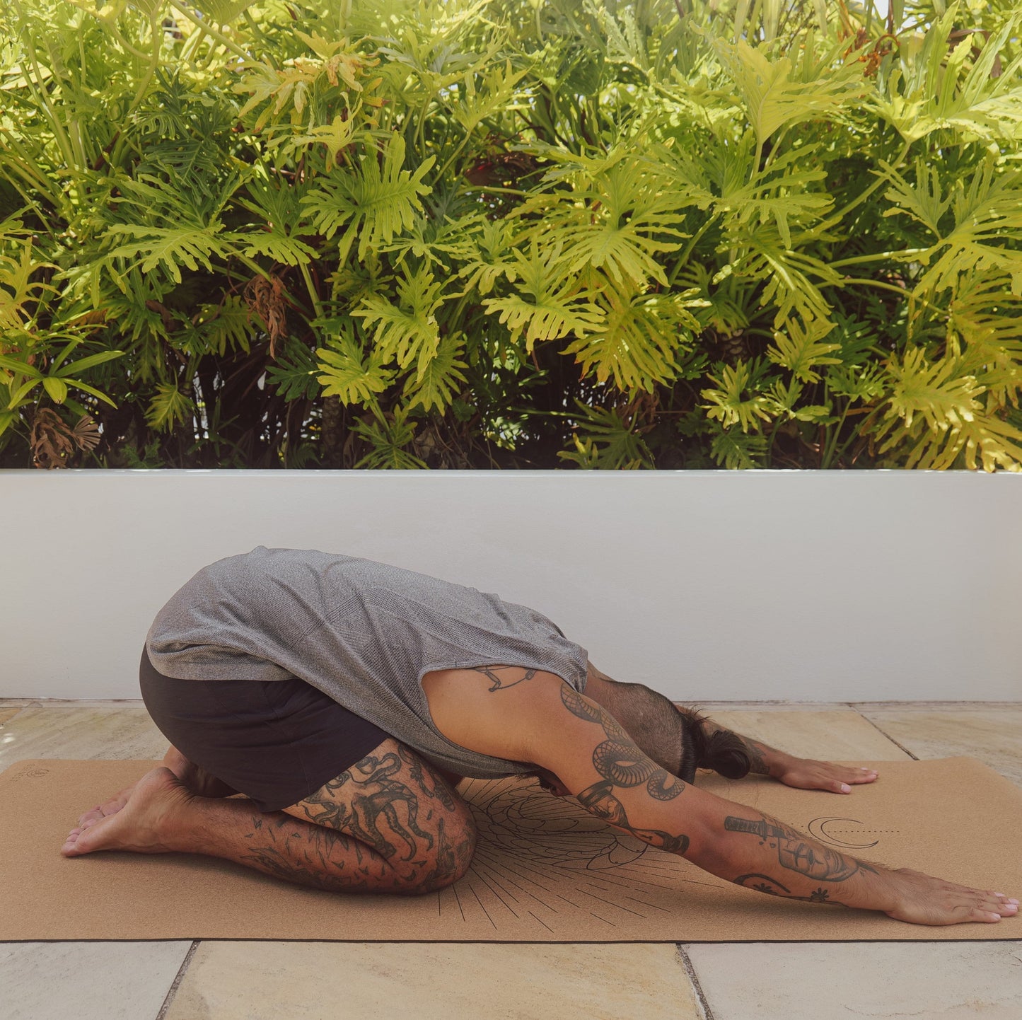 Man performing child's pose on moon serpent cork and natural rubber yoga mat.