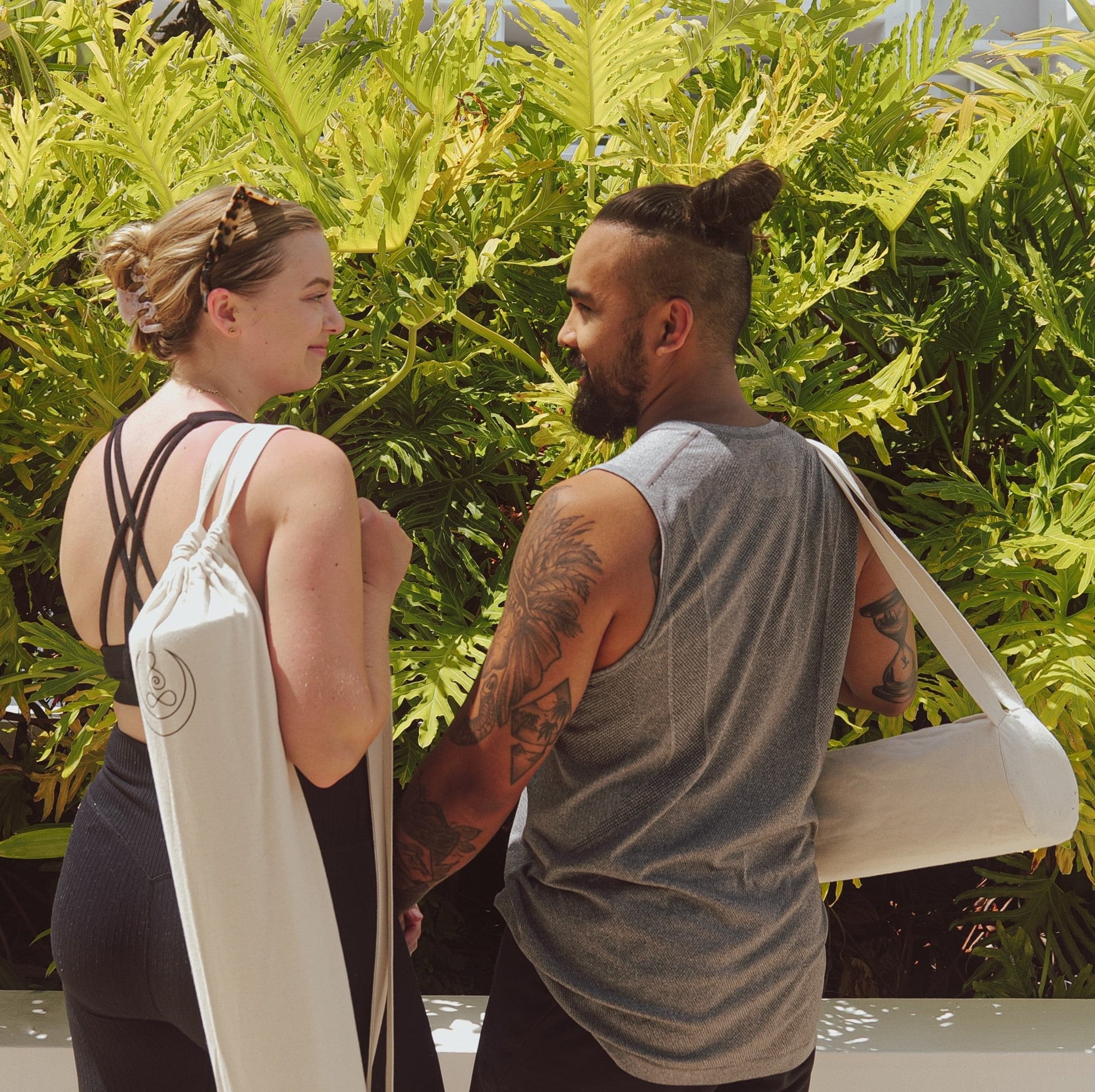 One woman and one man wearing OGI NEST cotton canvas yoga mat carry bags.