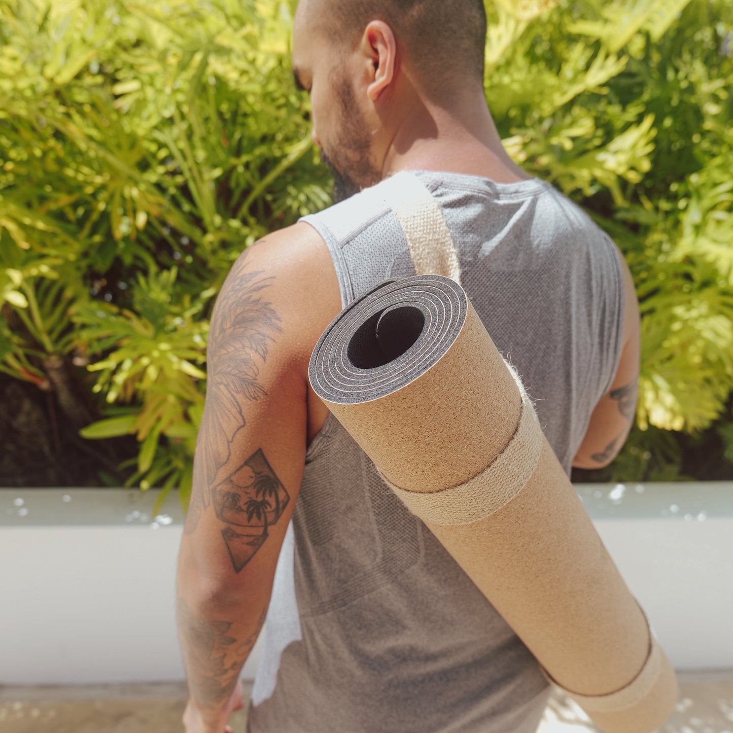 One man using OGI NEST jute carry strap to carry his cork and natural rubber yoga mat.